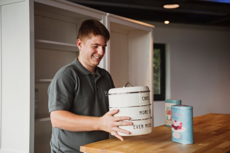 1. Fröhlicher Caterer bei Grand Frère mit Kuchenboxen in gemütlicher Atmosphäre.